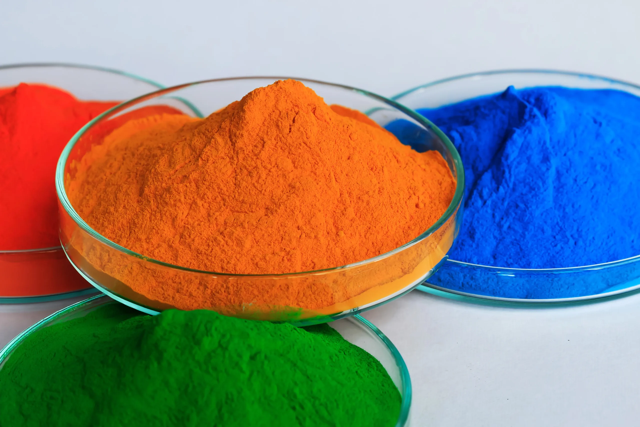 Gekleurde pigmentpoeders in rood, blauw, groen en oranje in laboratoriumschalen